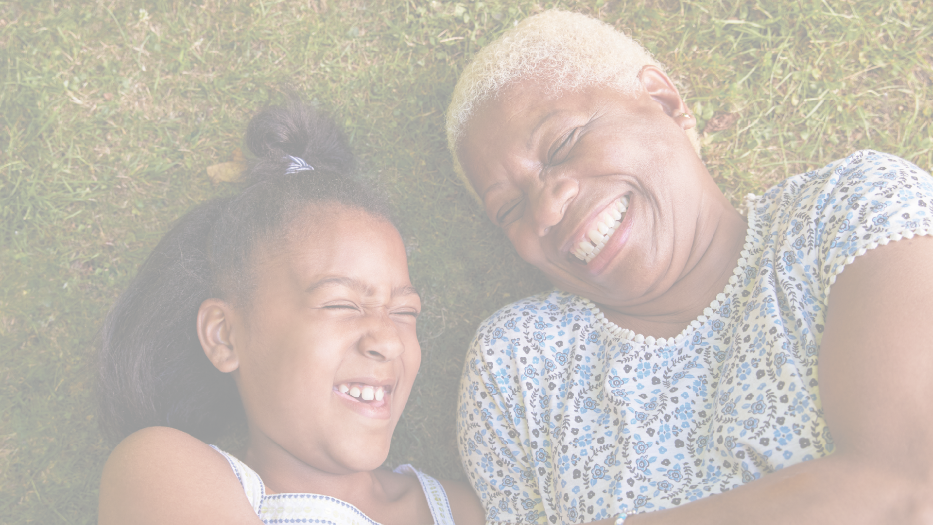 Black girl and grandmother lying on grass, overhead close up